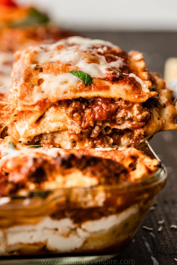 slice of lasagna being scooped out of baking dish