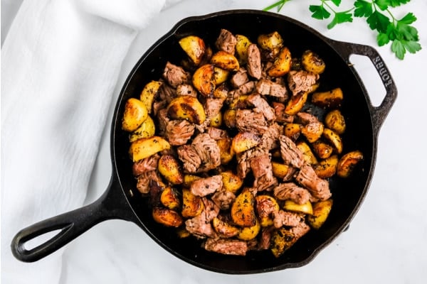 cast iron skillet with steak bites and potatoes