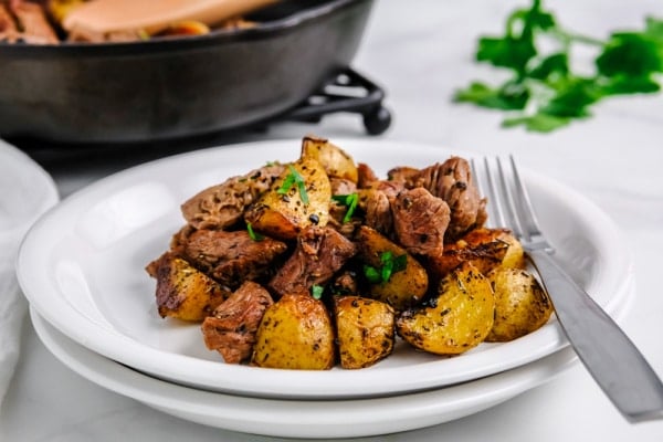 steak bites and potatoes on a white plate with a fork