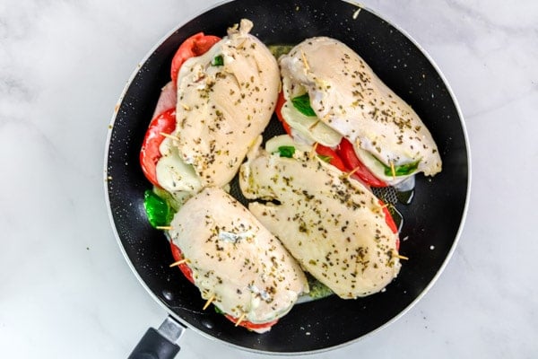 four chicken breasts cooking in a black skillet