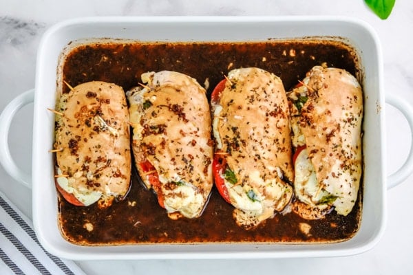 four chicken breasts covered with balsamic vinegar in a white casserole dish