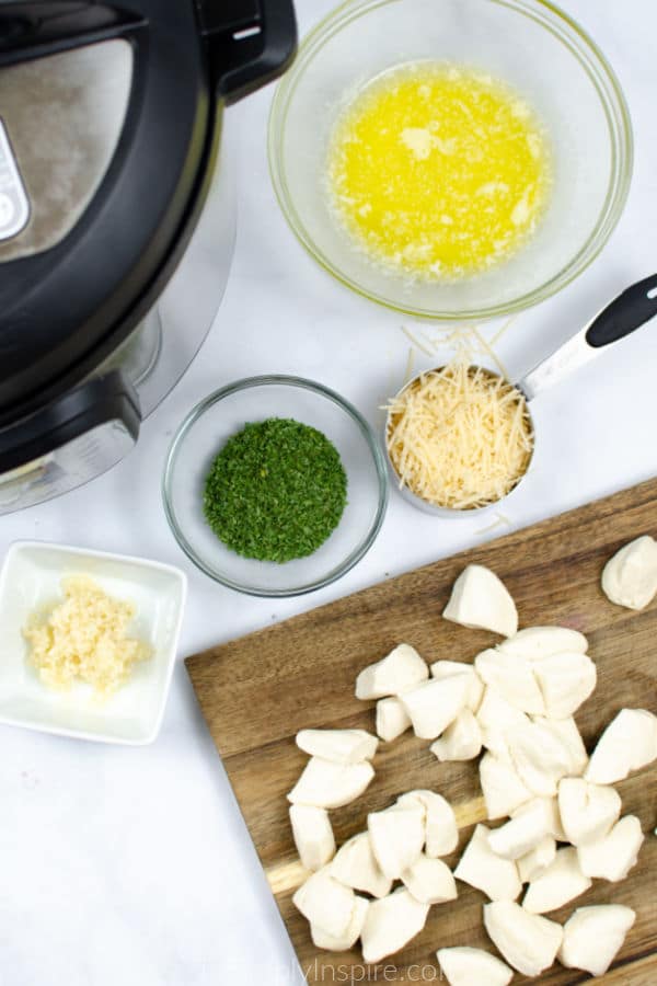 wood cutting board with break dough chunks surrounded by glass bowls of ingredients