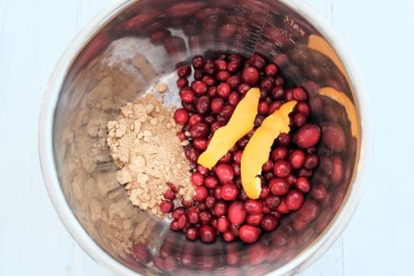 overhead of fresh cranberries, sugar, and orange slices in an instant pot