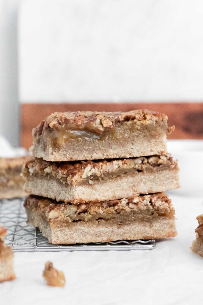 a stack of three pecan pie bars on a wire cooling rack