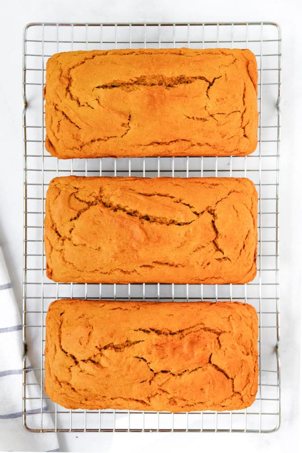 three loaves of sweet potato bread on a wire cooling rack