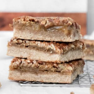 a stack of 3 pecan pie bars on a cooling rack