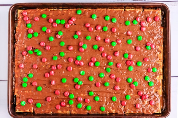 a pan of christmas crack recipe topped with red and green m&m's