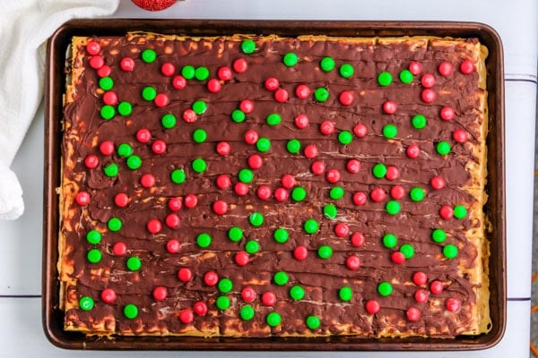 a pan full of saltine toffee covered in red and green candy