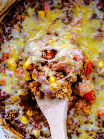 closeup of cheesy Mexican casserole being scooped out of a slow cooker