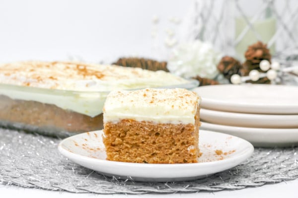 a slice of gingerbread cake with cream cheese frosting with a full pan in the background