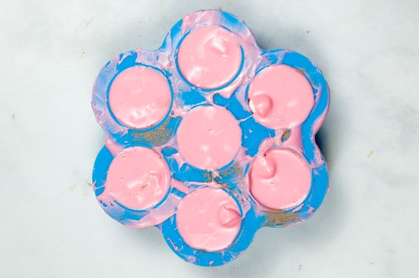 seven round silicon molds filled with melted pink candy chocolate