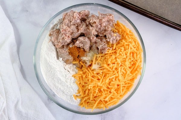 shredded cheese, sausage, and bisquick in a glass mixing bowl