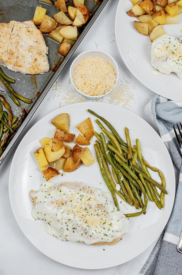 a white plate with creamy chicken, died potatoes and green beans