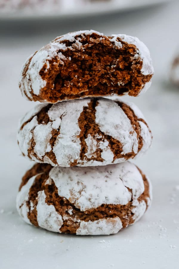 a stack of three chocolate crinkle cookies with a bite taken out of the top cookie