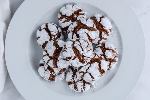 a white plate full of chocolate crinkle cookies