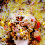 closeup of a spoonful of mexican casserole covered with melted cheese