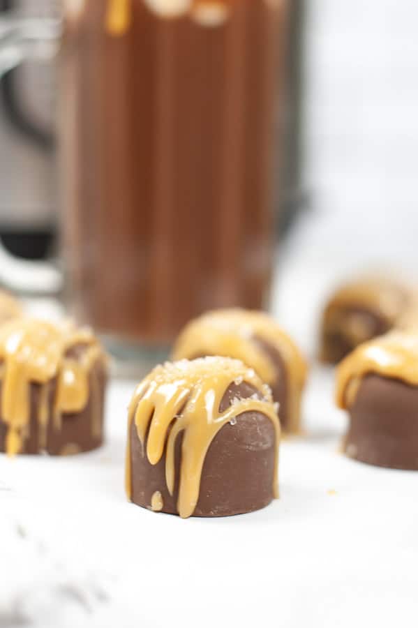several hot cocoa bombs drizzled with caramel on a table