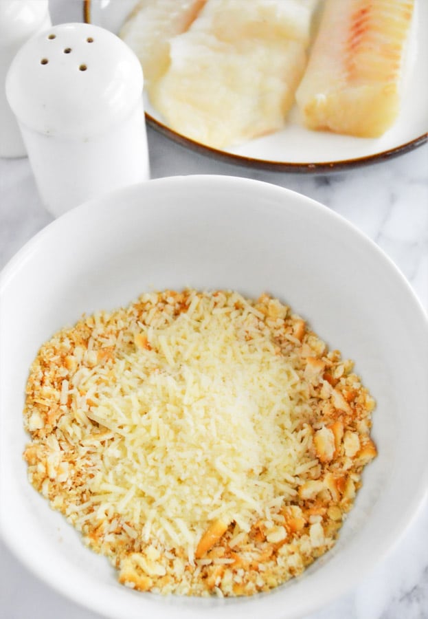 a white bowl with breadcrumbs and parmesan cheese