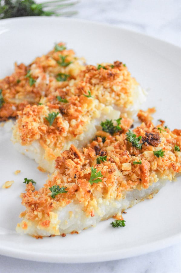 a white plate with three oven baked cod fillets topped with a crispy topping