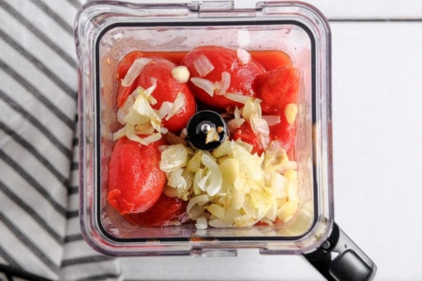 a blender with tomatoes and onions inside