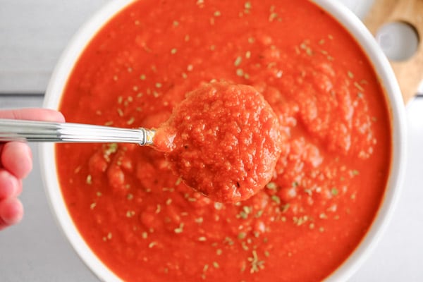 closeup of a scoop of marinara sauce over top of a bowl