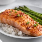 salmon fillet with maple soy glaze on a bed of white rice with asparagus on the side