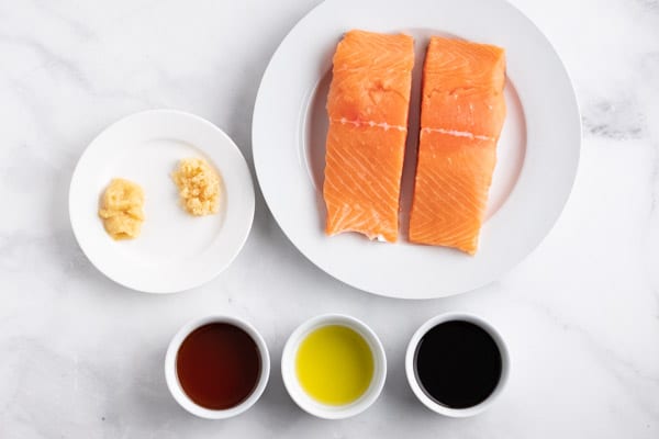 raw salmon on a plate with bowls of soy, maple syrup, and oil