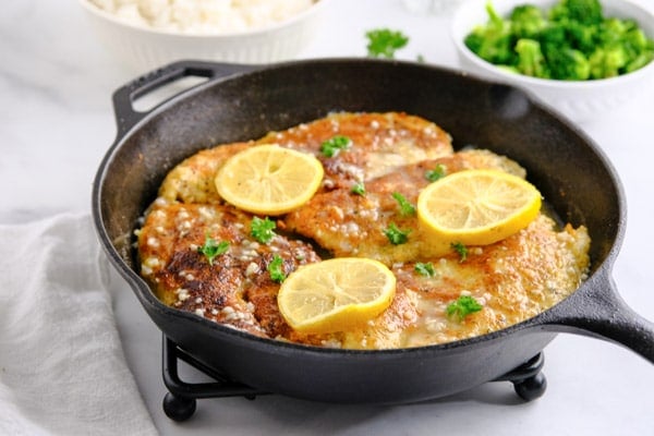a cast iron skillet with breaded cooked chicken breasts