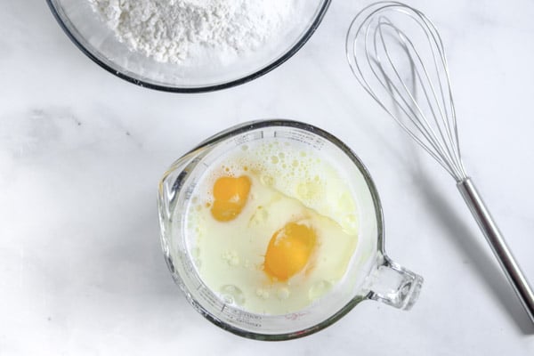 two eggs in a measuring cup with milk