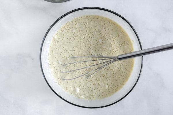 pancake batter in a glass bowl with a whisk