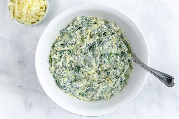 spinach artichoke cream cheese mixed together in a white bowl 