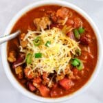 closeup of bowl of classic chili topped with cheese and green onion slices