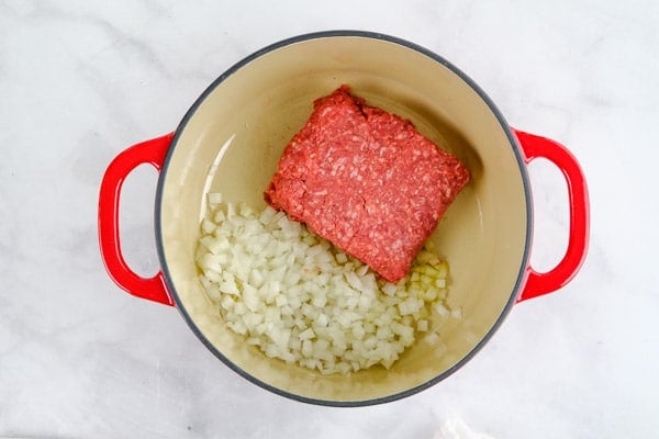 raw ground beef and diced onions in a dutch oven