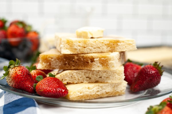 a stack of sheet pan pancakes on a glass plate with strawberries