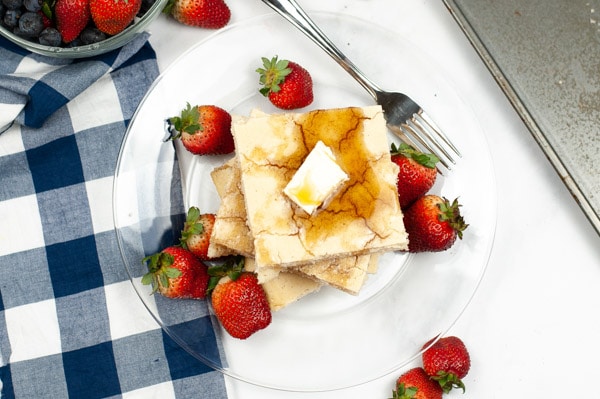 one pan pancakes on a glass plate with strawberries with a blue and white checker napkin