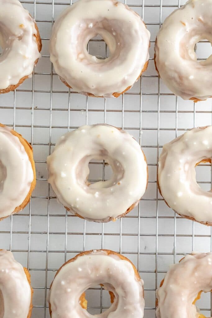 several glazed donuts on a silver wire rack