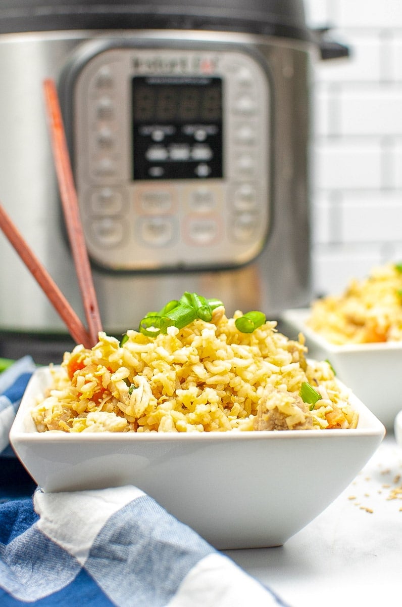 a white bowl with chicken fried rice with chop sticks in front of of instant pot