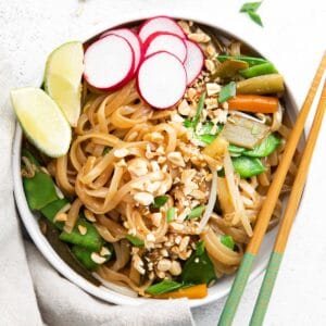 closeup of vegetarian pad thai with rice noodles, crushed peanuts and slices of radish