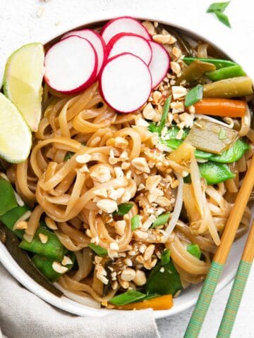 closeup of vegetarian pad thai with rice noodles, crushed peanuts and slices of radish