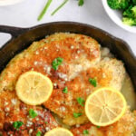 parmesan crusted chicken breasts in a cast iron pan topped with 3 lemon slices