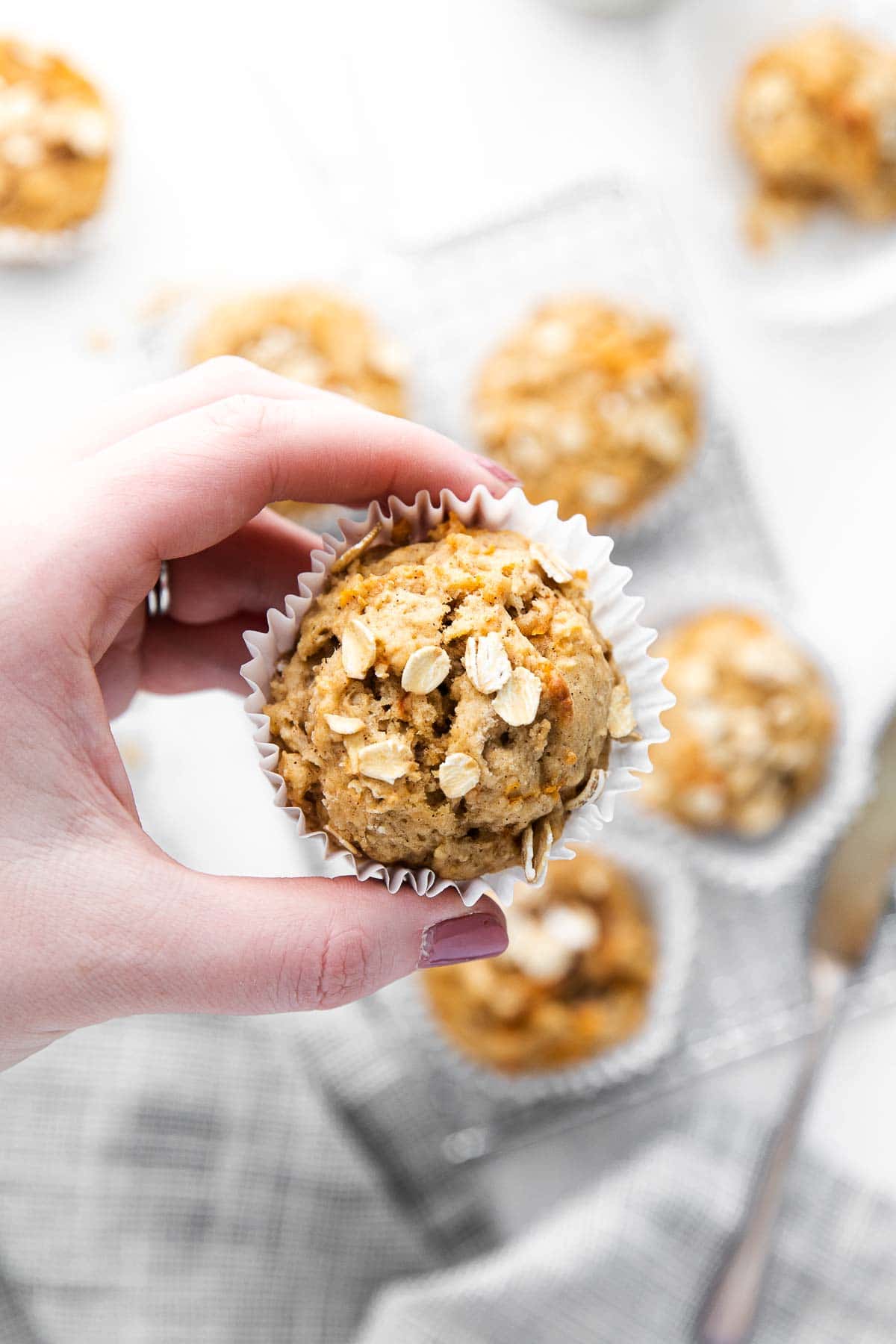 woman hand holding a muffin topped with oats
