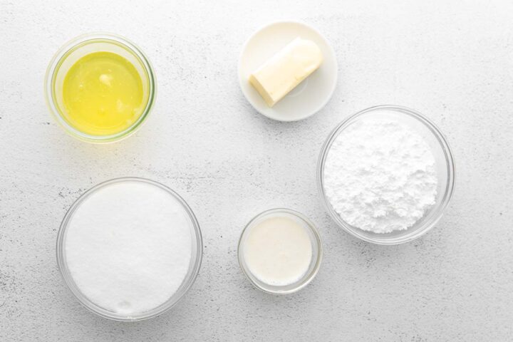 several glass bowls filled with ingredients - flour, sugar, eggs whites and butter