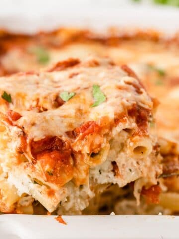 a slice of baked ziti being scooped out of a casserole dish