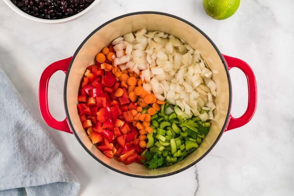 diced onion, celery, red peppers and carrots in a pot