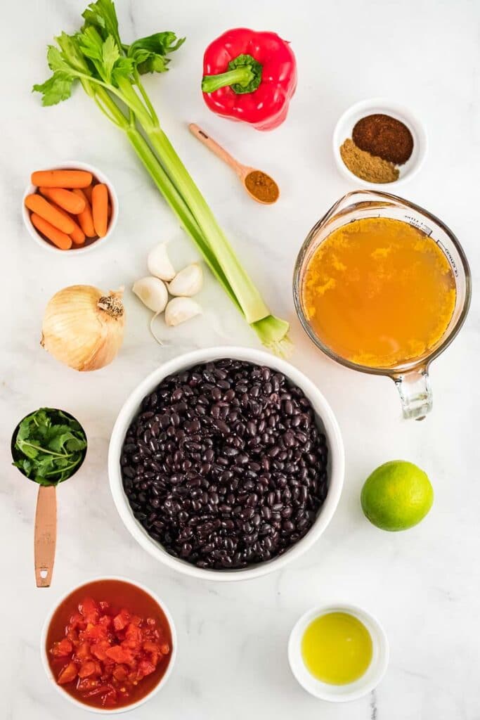 several ingredients for black bean soup in white bowls