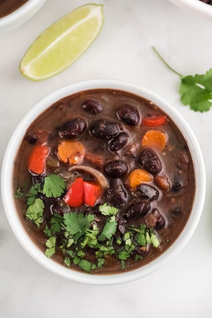 white bowl with black bean soup topped with cilantro