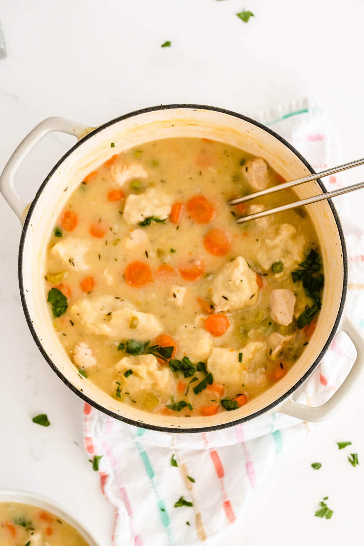 big white pot of chicken and dumplings topped with fresh parsley