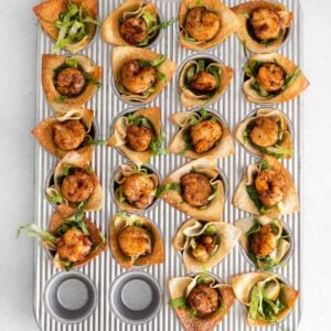 a mini muffin tin fulled with wonton wrapper cups and topped with shrimp
