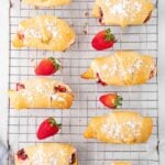 several crescent rolls on a wire cooling rack with fresh strwberries