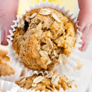 A hand holding a muffin with oats and a banana.